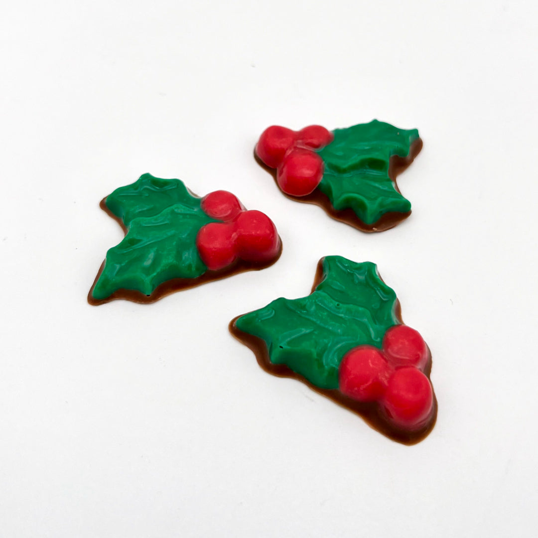 Christmas holly plant in chocolate, with 2 green leaves and 3 red berries.