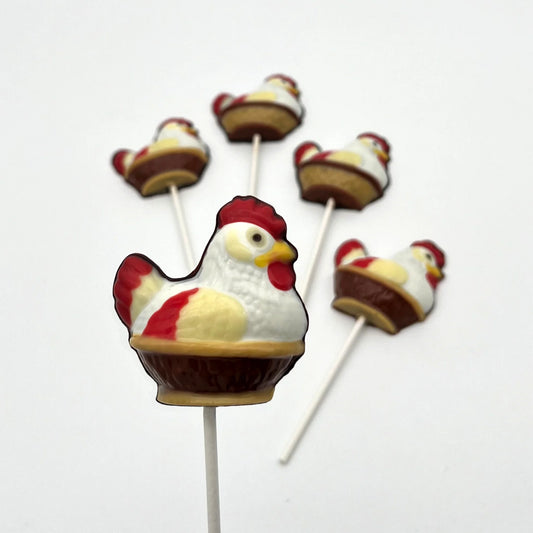 Chocolate hen sitting in a brown woven-style basket, coloured in white, cream, red, black and yellow - just like the real thing!