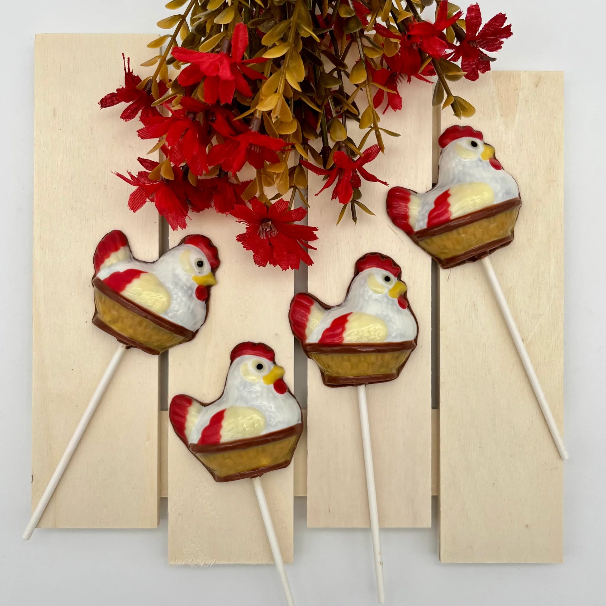 Chocolate hen sitting in a brown woven-style basket, coloured in white, cream, red, black and yellow - just like the real thing!