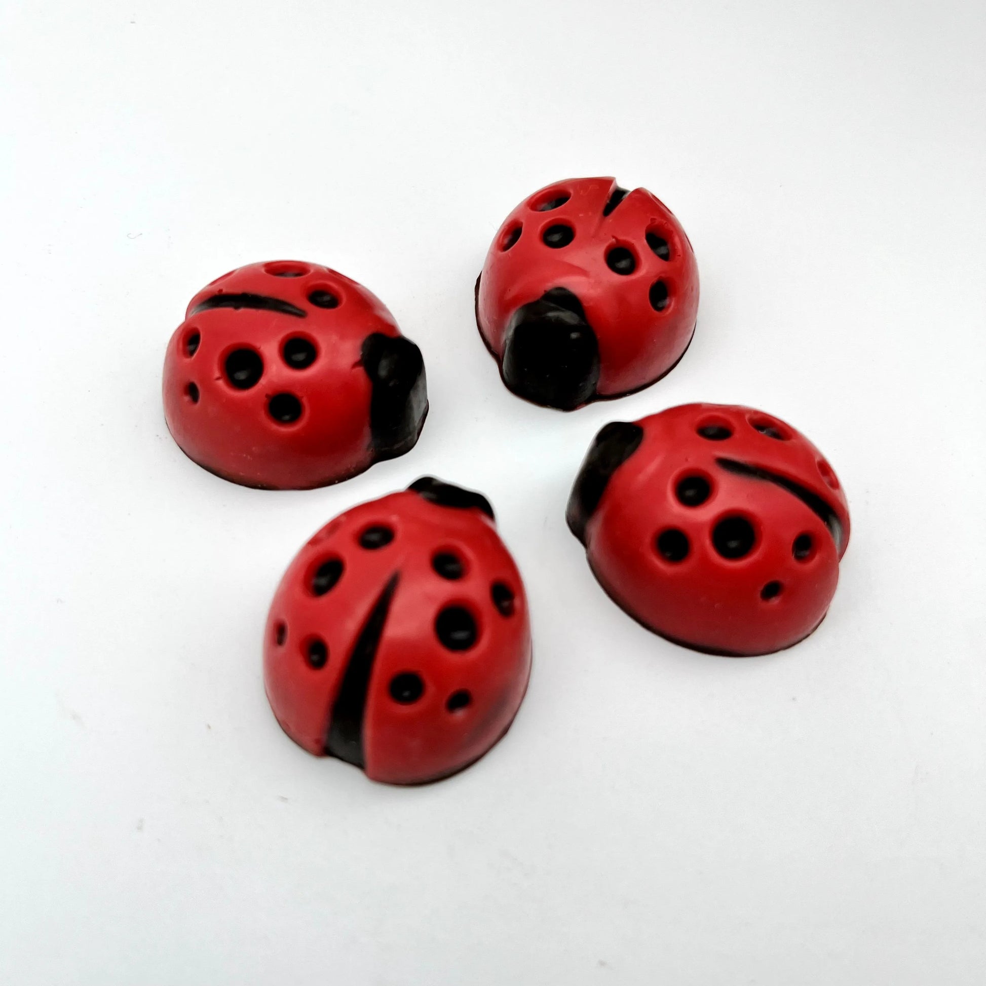 Red ladybug with black spots and head, all made of chocolate.
