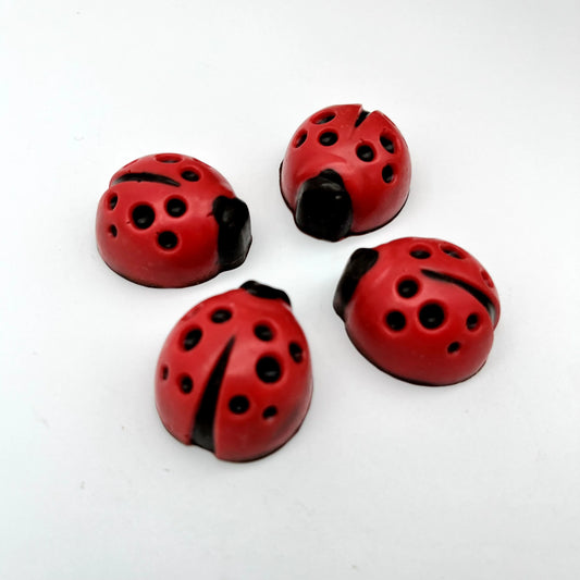 Red ladybug with black spots and head, all made of chocolate.