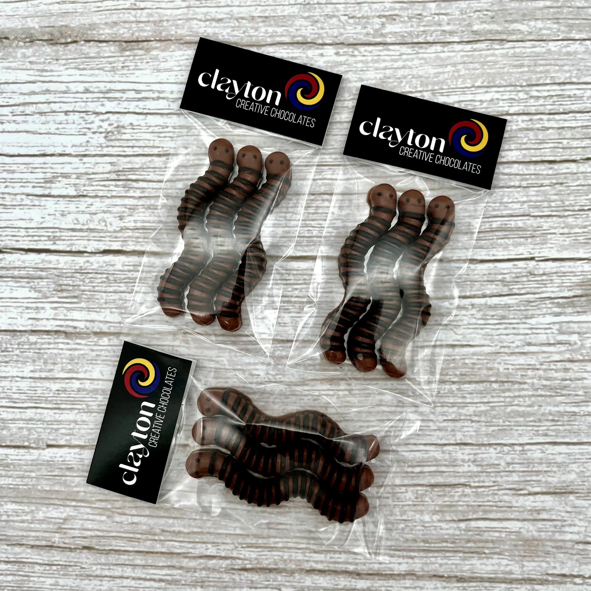 Realistic-looking brown and black chocolate worms, displayed in sets of 3 in Clayton Creative Chocolate packaging.