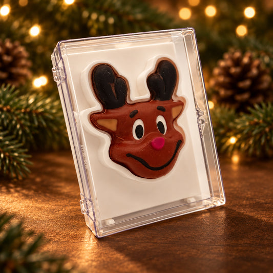 Smiling chocolate reindeer face with dark antlers and a red nose in a clear acrylic gift box.