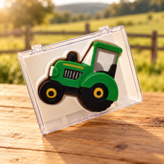 Green chocolate tractor with black tires and yellow wheel centres in a clear acrylic gift box.