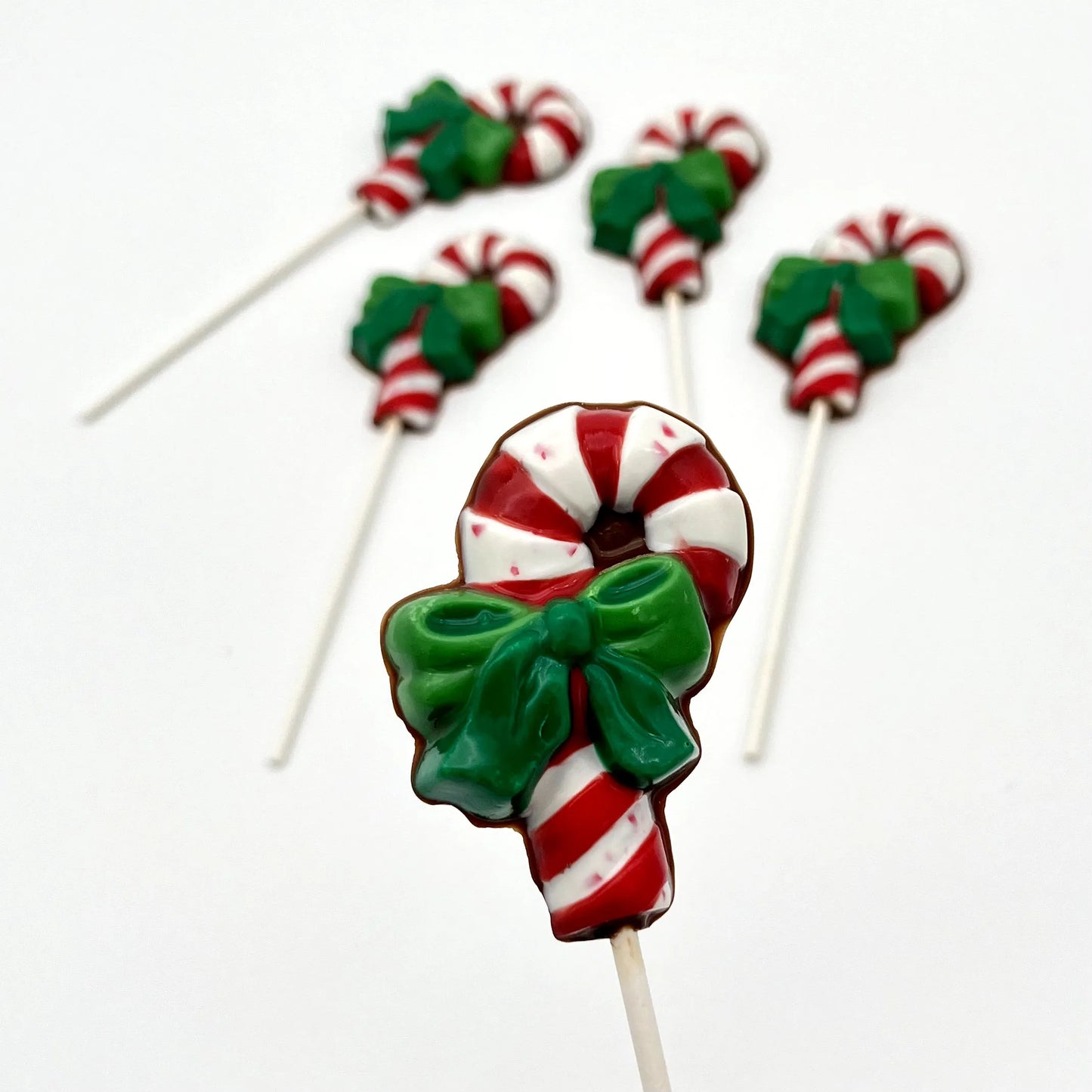 Red and white striped candy cane chocolate sucker with two-toned green bow.
