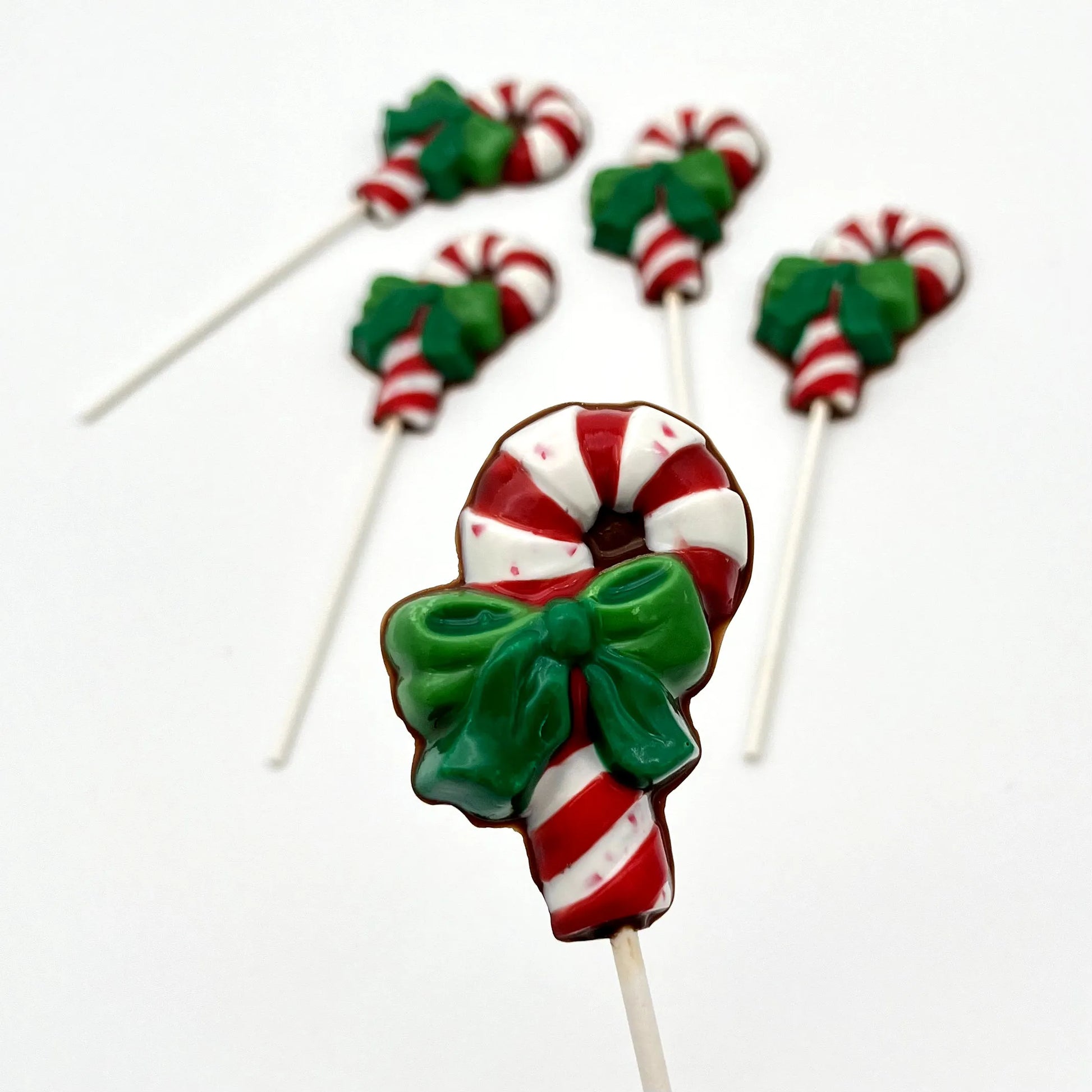 Red and white striped candy cane chocolate sucker with two-toned green bow.