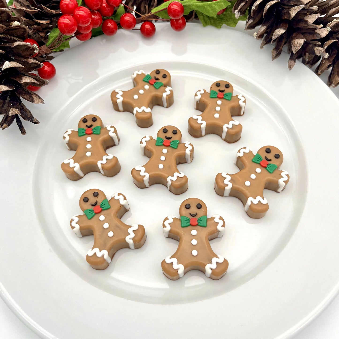 Plate holding chocolate gingerbread men, coloured with traditional brown "cookie" colour, white buttons and trim, black eyes and smile, green and red bowtie.