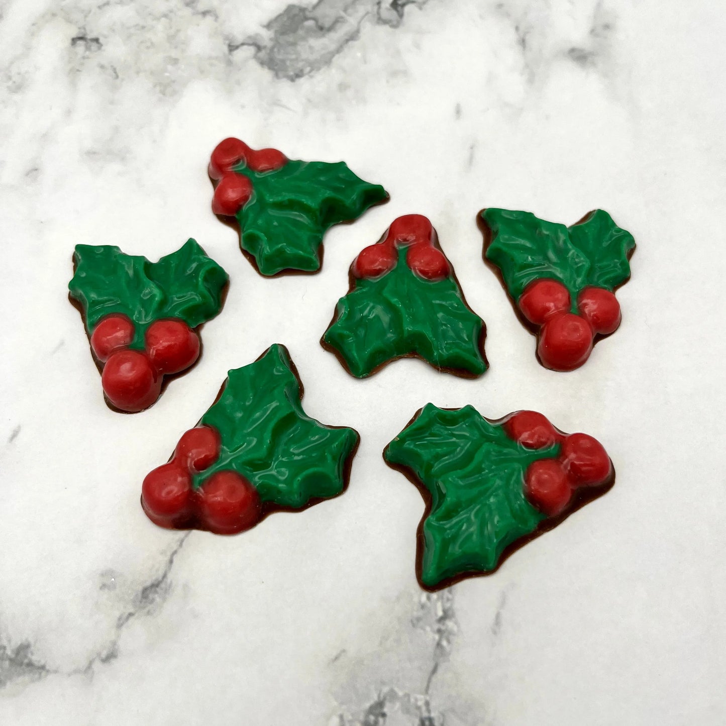 Christmas holly plant in chocolate, with 2 green leaves and 3 red berries.