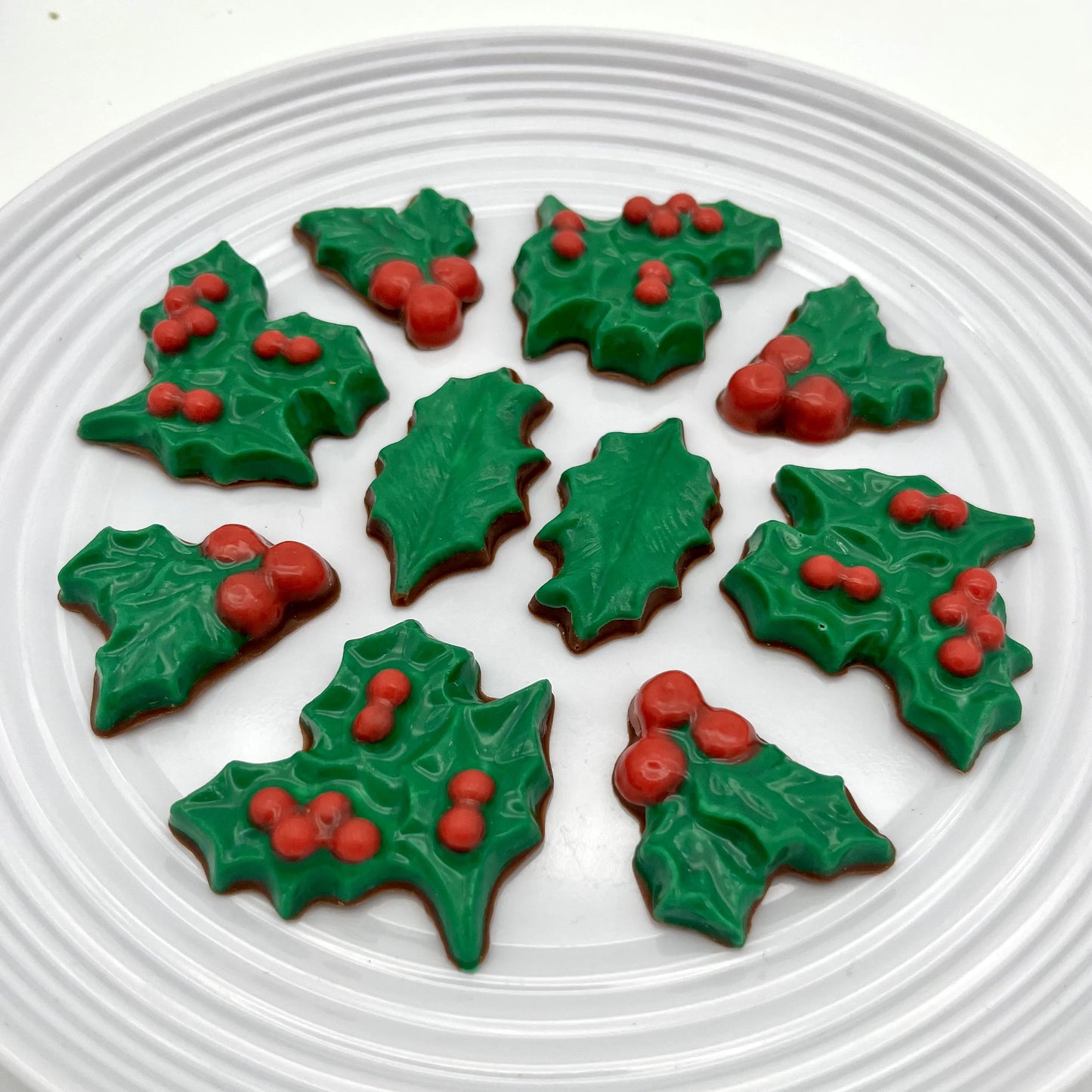 Variety of chocolates with dark green holly leaves and red berries. Perfect as decorations on a festive cakes.