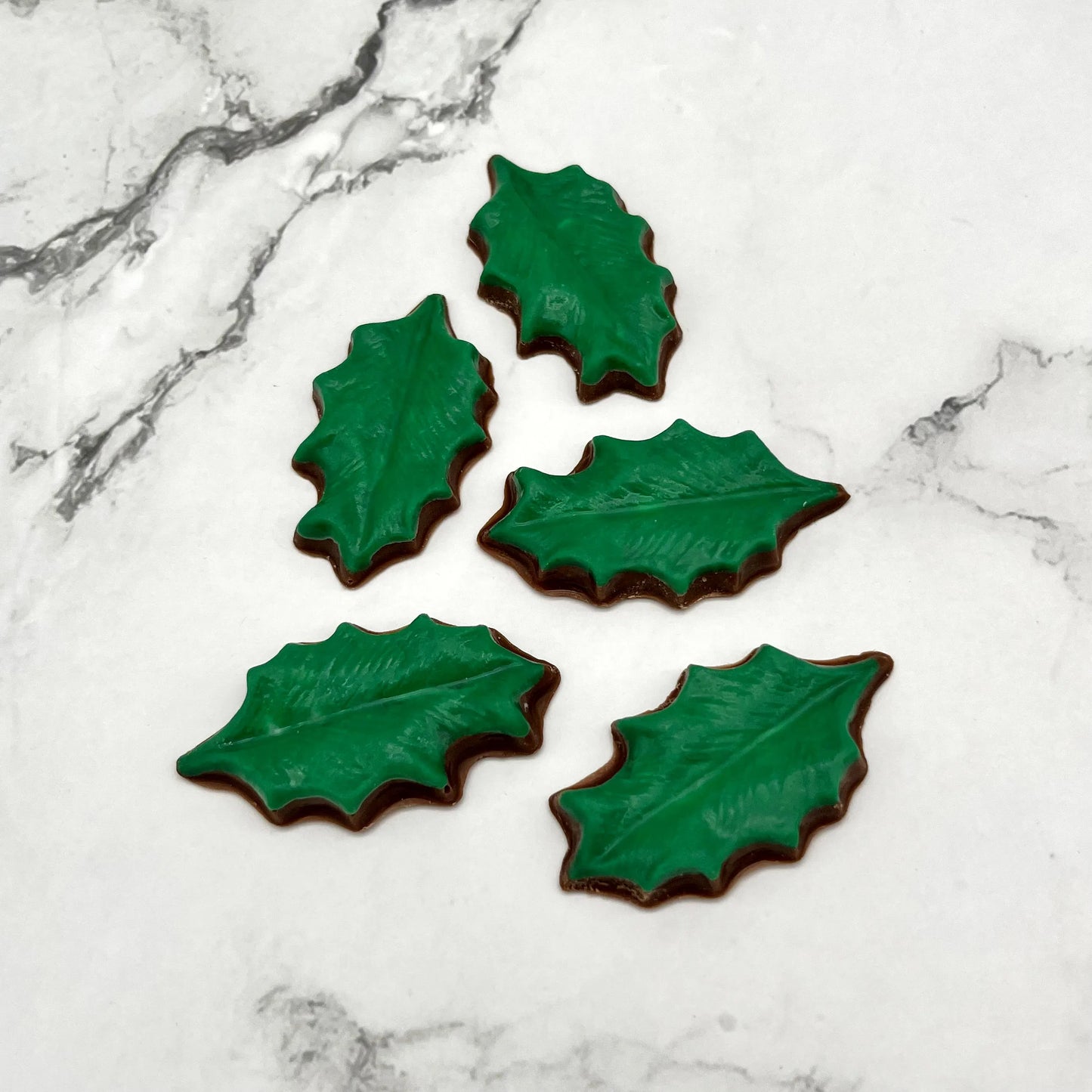 Chocolate holly leaves coloured in dark green; perfect accent piece for seasonal party table displays or cake decorations.