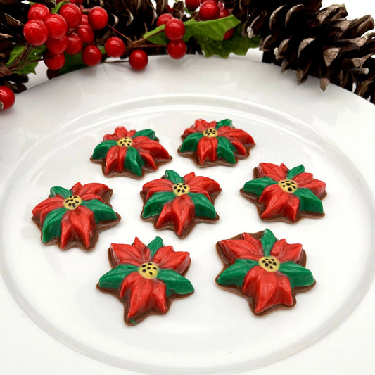 Chocolate poinsettias with red petals, green leaves and a yellow centre with black dots.