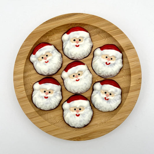 Round chocolate Santa heads, coloured with full white beards, moustaches, red smiles, cheery pink noses and Santa hats.