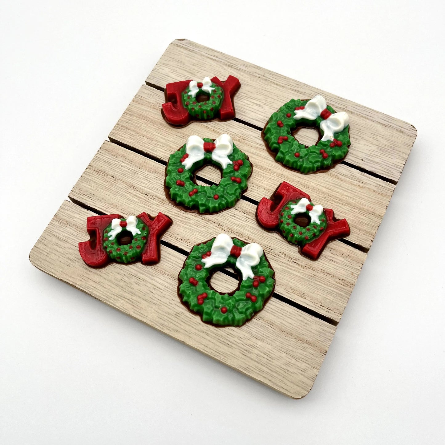 Chocolate Christmas wreaths, plus the word JOY; the J and Y are red, and the O is a wreath. All coloured in traditional green with red berries and white bow.