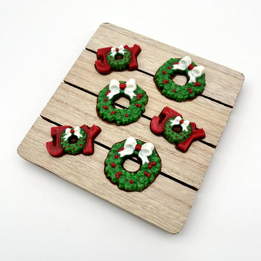Chocolate Christmas wreaths, plus the word JOY; the J and Y are red, and the O is a wreath. All coloured in traditional green with red berries and white bow.