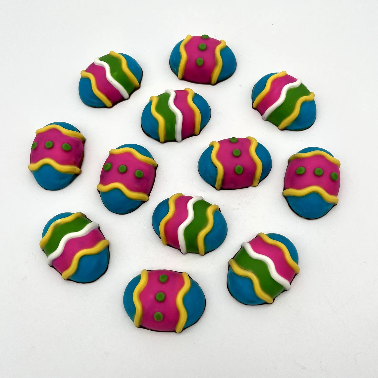 3 life-sized chocolate Easter eggs, decorated with stripes and dots in white and vibrant yellow, blue, pink and green.