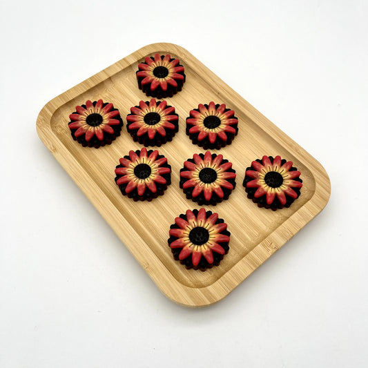 Beautiful chocolate gerbera daisies in blended yellows, oranges and reds on a black background.