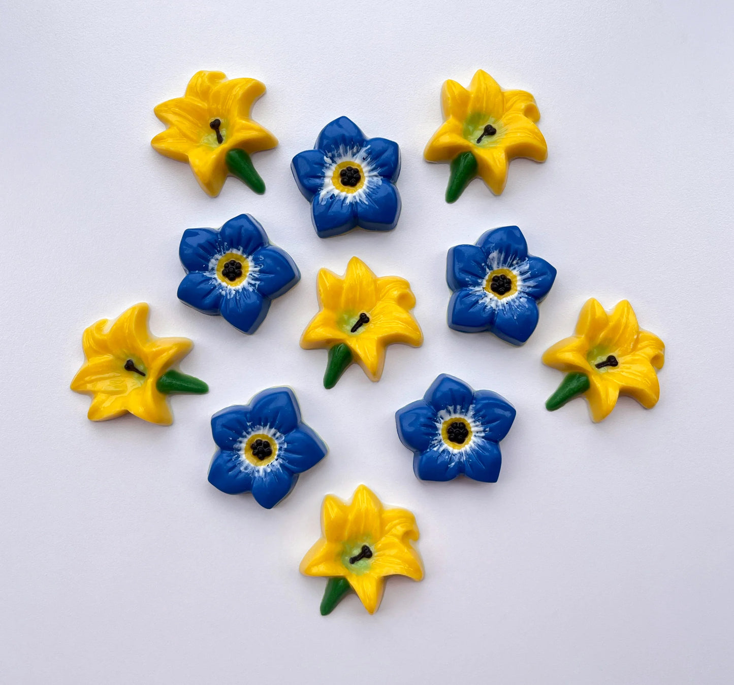 Lily flower in classic yellow, green and black. Pictured with blue forget-me-not flowers. All made from chocolate.