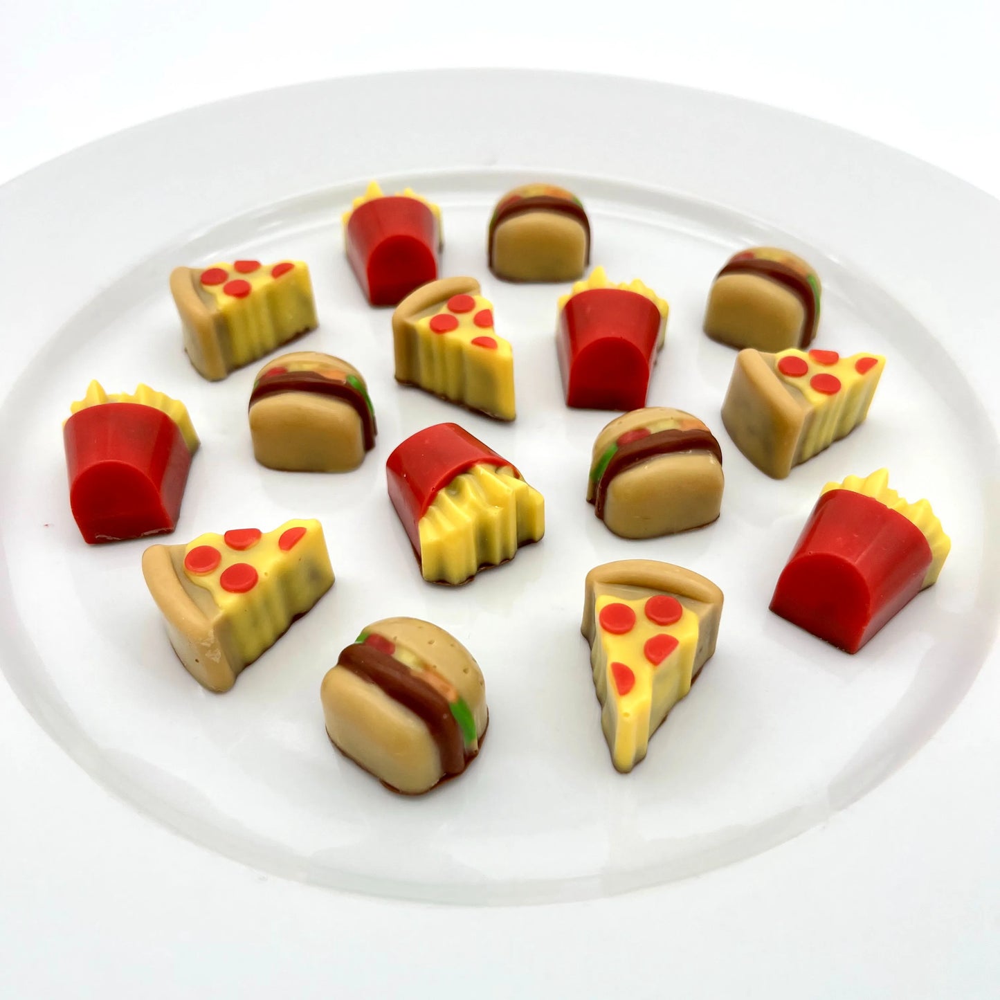 Realistic-looking brightly-coloured pizza slices, burgers, and fries in a box, arranged on a plate. All made from chocolate.