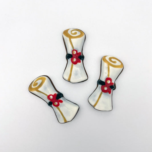 3 white graduation scrolls made of chocolate, with a black band, red bow and gold trim.