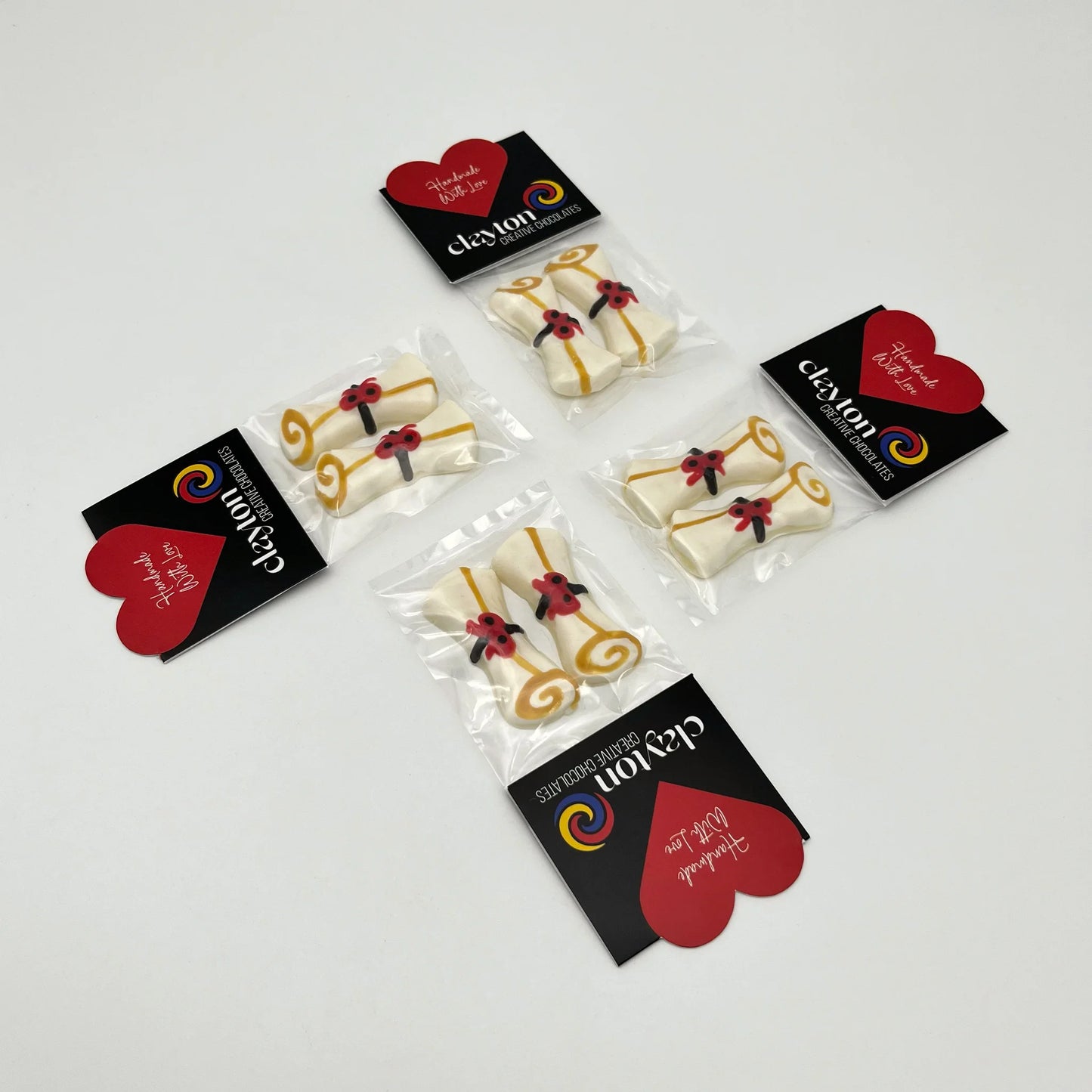 3 white graduation scrolls made of chocolate, with a black band, red bow and gold trim. Packaged in pairs.
