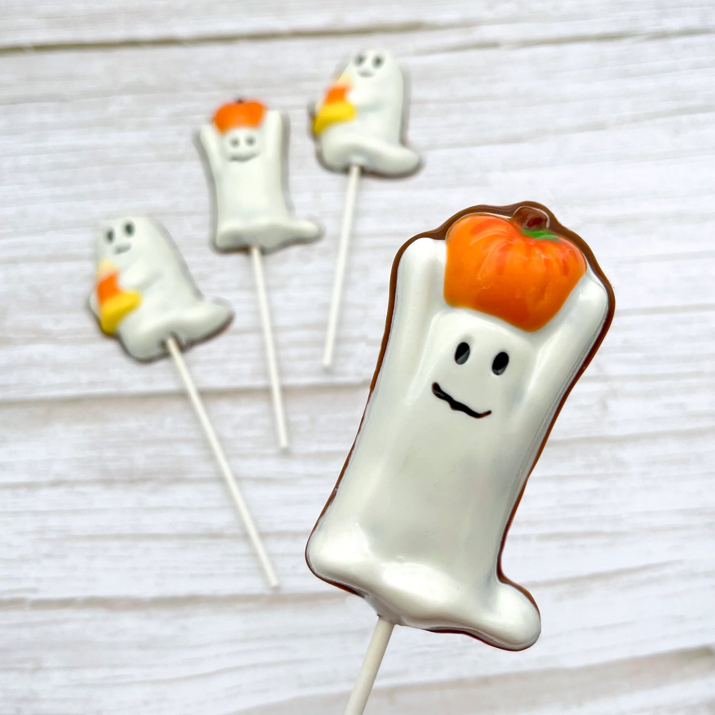Halloween-themed chocolate sucker of a ghost holding a pumpkin on its head.