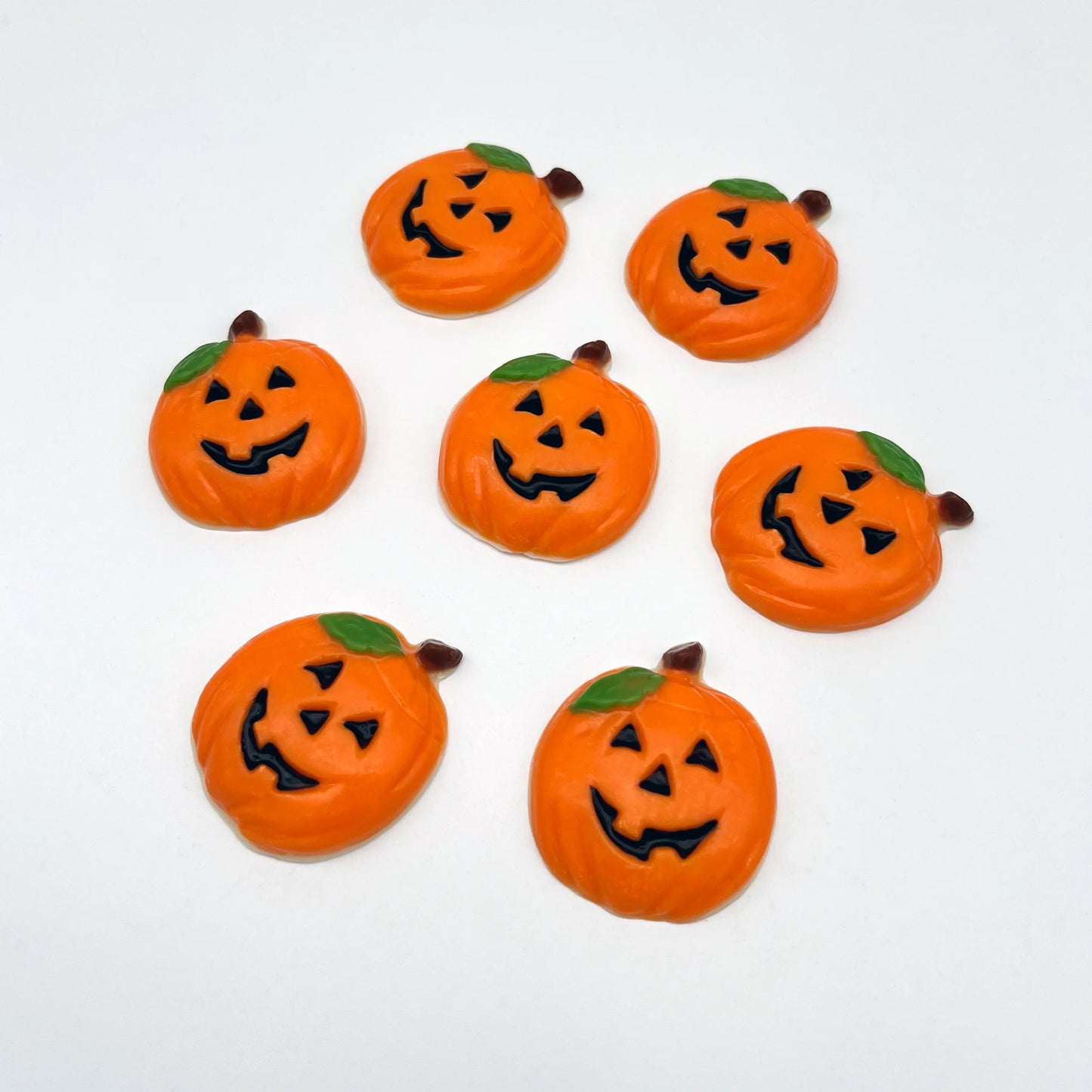 Fun orange pumpkins with traditional carved eyes, nose and mouth in black, with a green leaf and brown stem. All made of chocolate.