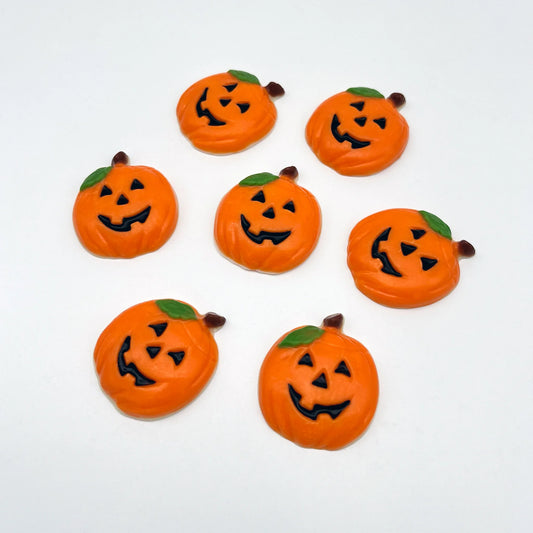 Fun orange pumpkins with traditional carved eyes, nose and mouth in black, with a green leaf and brown stem. All made of chocolate.