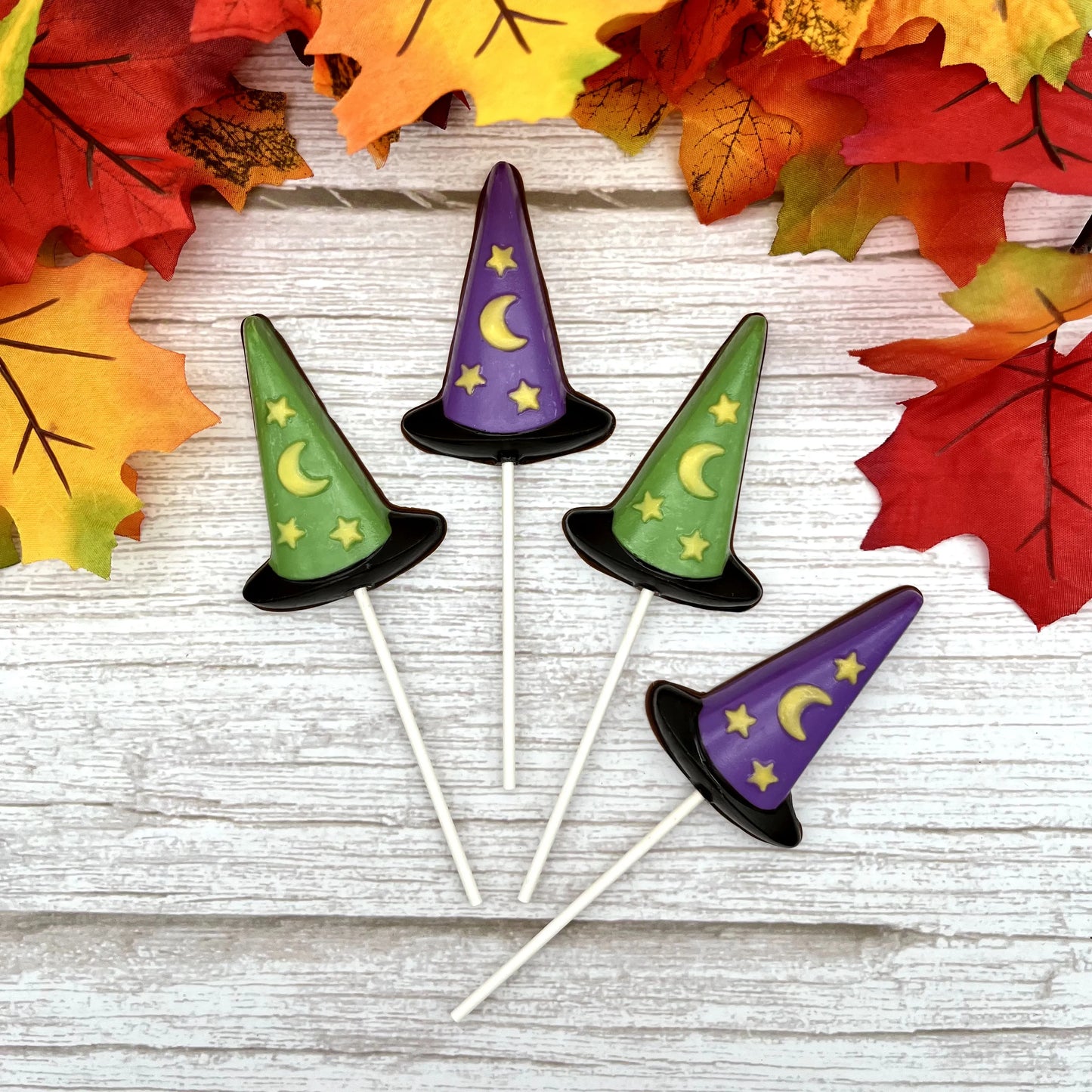 Black, purple and green witch hat suckers with yellow stars and moon; all made from chocolate.