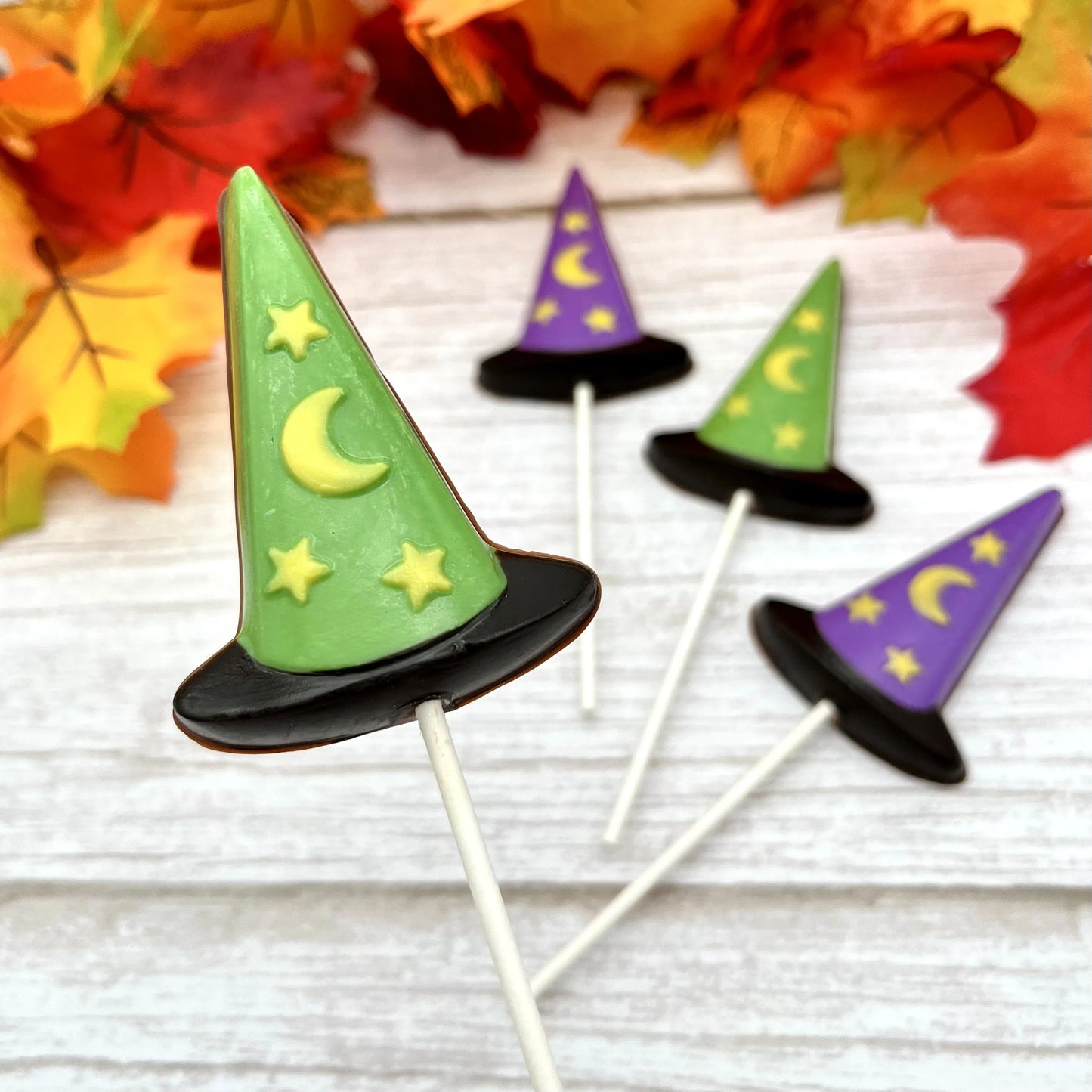 Black, purple and green witch hat suckers with yellow stars and moon; all made from chocolate.