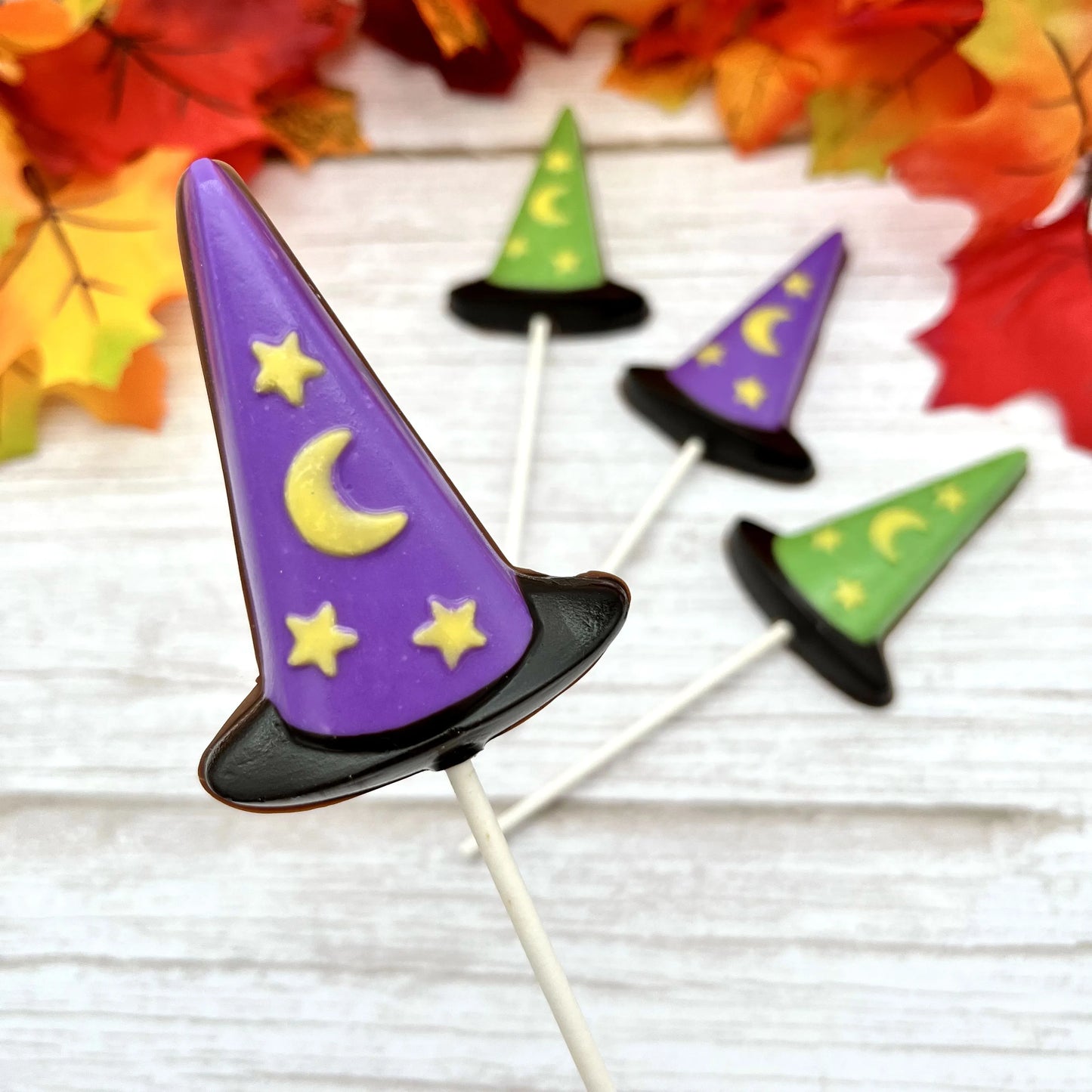 Black, purple and green witch hat suckers with yellow stars and moon; all made from chocolate.