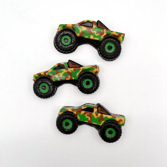Three camo-patterned monster truck-shaped chocolates with green and black wheels and detailing.