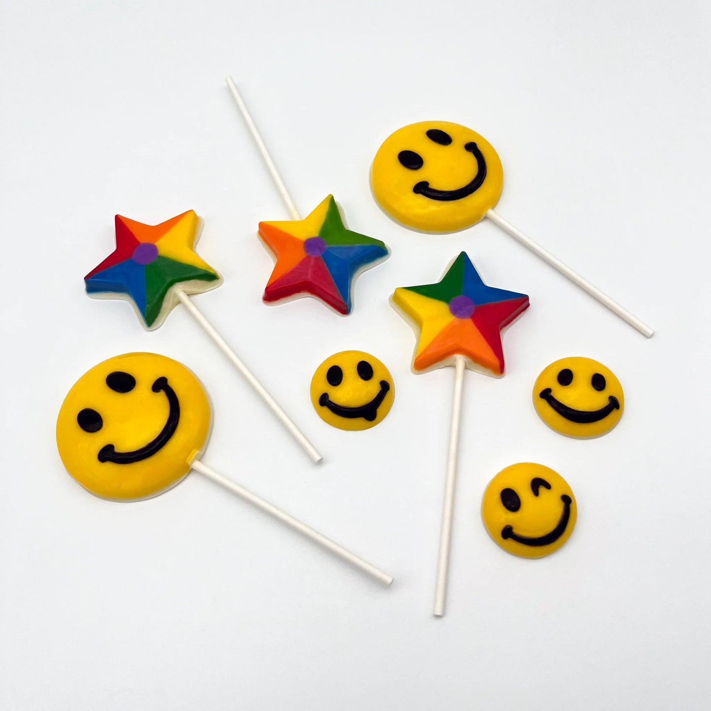 Jumbo version of the classic yellow and black smile emoji, but made from chocolate. Pictured with smaller smiling emojis and rainbow suckers.