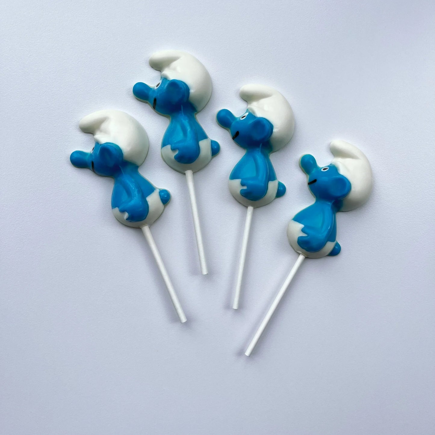 Side profile of 4 blue and white Smurf suckers, filled with milk chocolate.