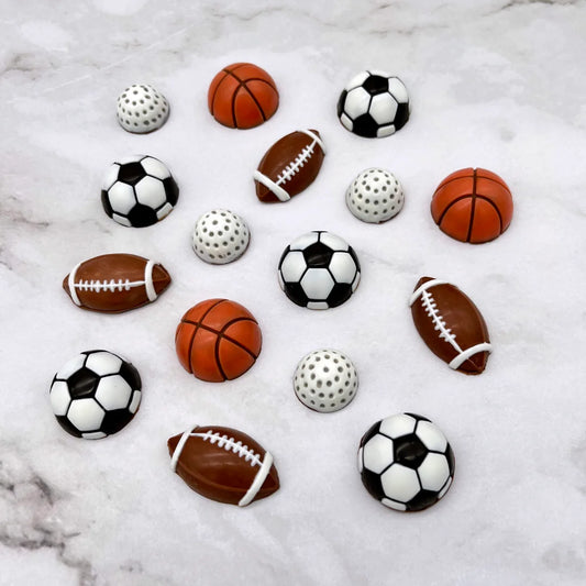 Soccer, football, golf and basketball sports balls, all made of chocolate. Decorated in typical sport ball colours.