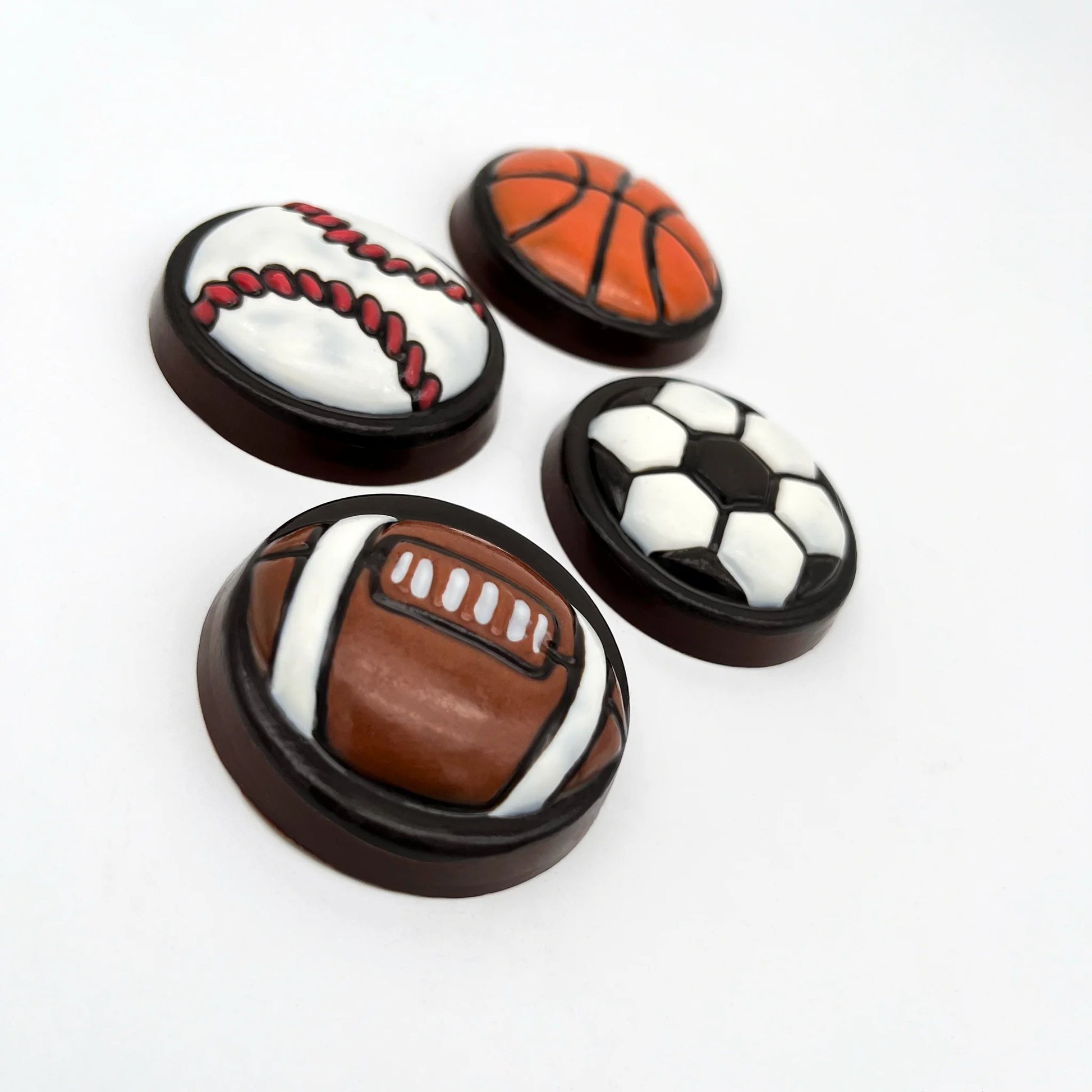 Large, round, medallion-style sports balls made from chocolate. Basketball, soccer, football and baseball hand-painted in traditional ball colours.