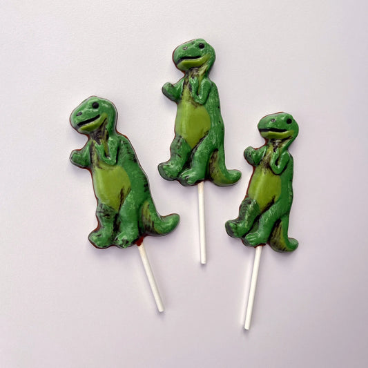 Standing T-Rex suckers made out of chocolate, coloured in 2-toned green and black.