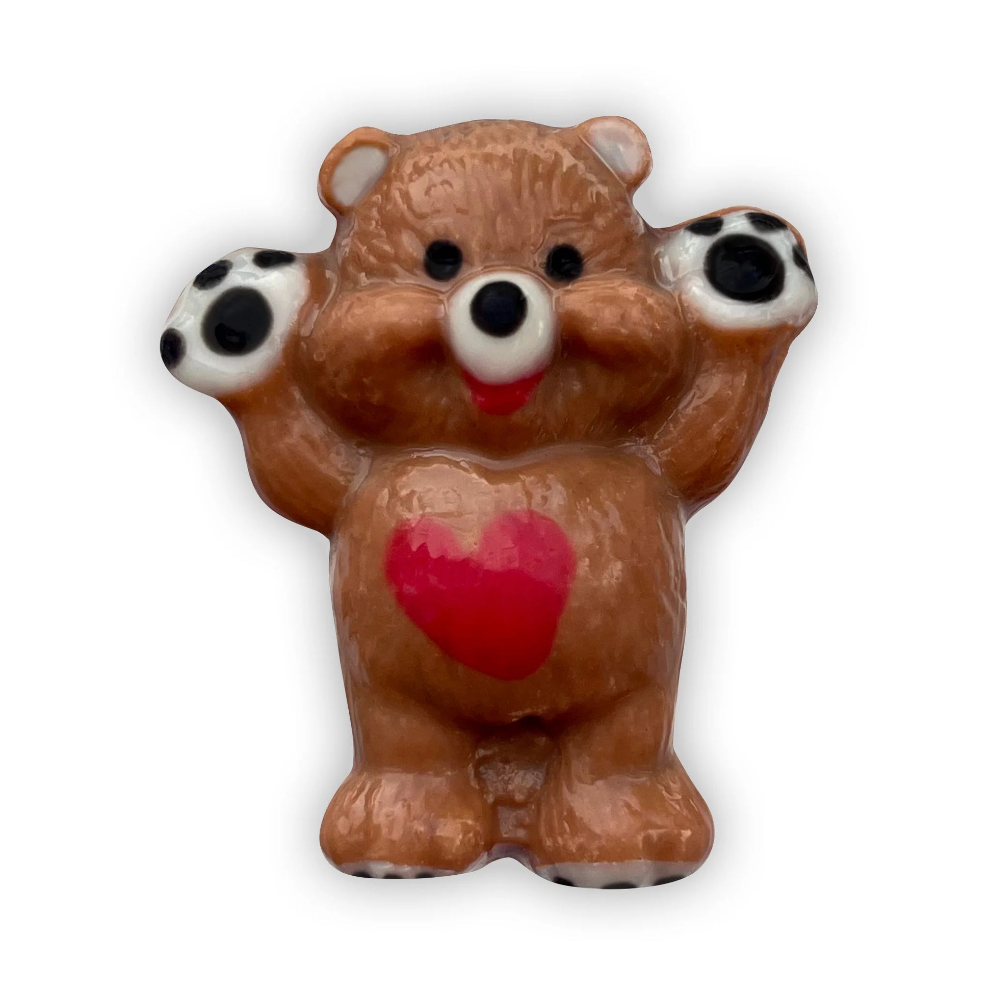 Chocolate bear standing and waving, decorated in brown and beige, with a red heart on its tummy and black paws. 