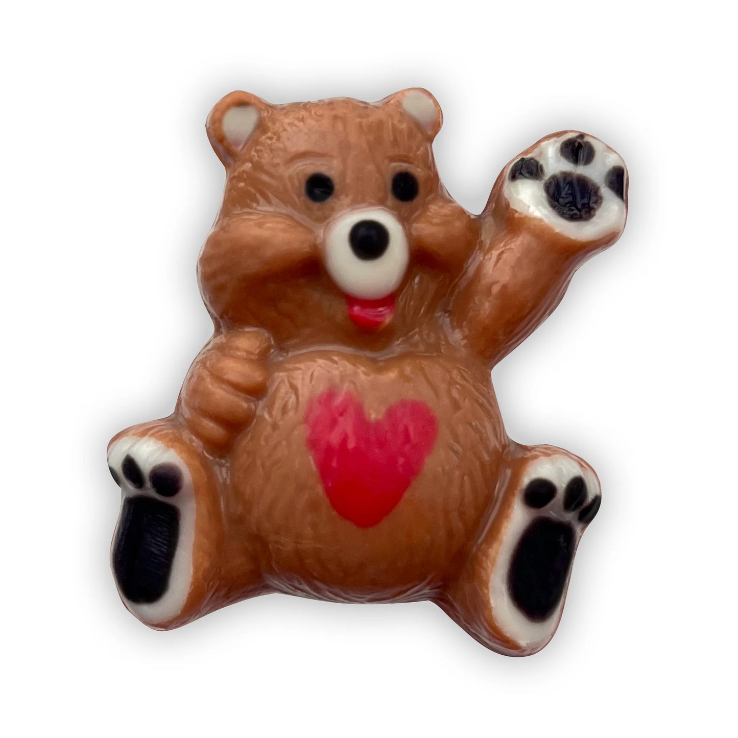 Chocolate bear sitting down and waving, decorated in brown and beige, a red heart on its tummy and black paws. 
