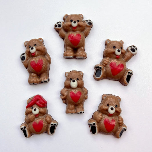 Six different chocolate bears in different positions, all decorated in brown, with red hearts on their tummies and black paws. 