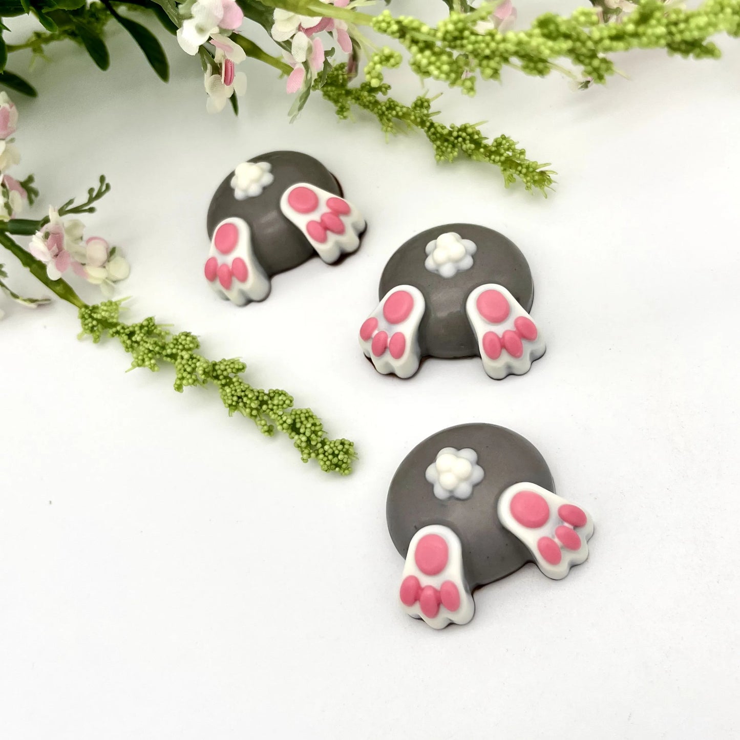 Three fun grey-coloured chocolate baby bunny butts with little pink toes and white tails.