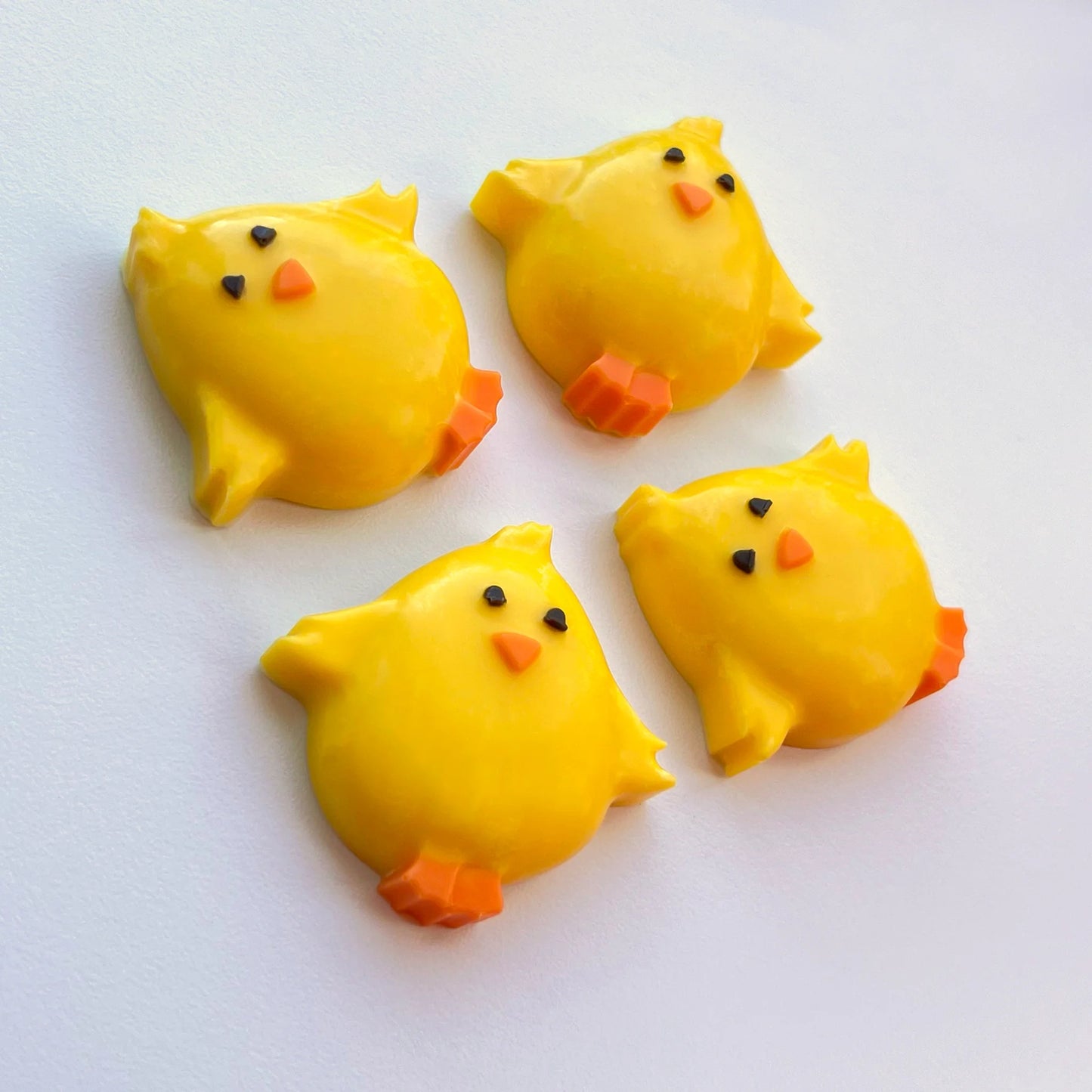 Adorable chubby yellow chicks made from chocolate, with smiling eyes, little orange feet and bills, all flapping their wings.