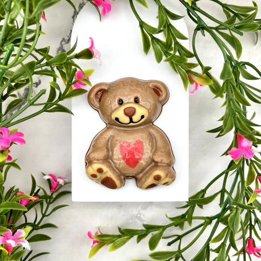 Bear stuffie made from chocolate. Two-toned brown body with cream ears and paws, black eyes and smile, and a red heart on its tummy.