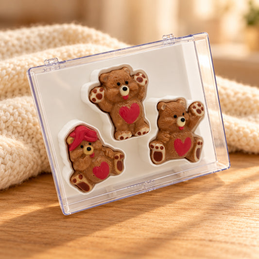 Three chocolate teddy bears with red hearts in a clear acrylic gift box.