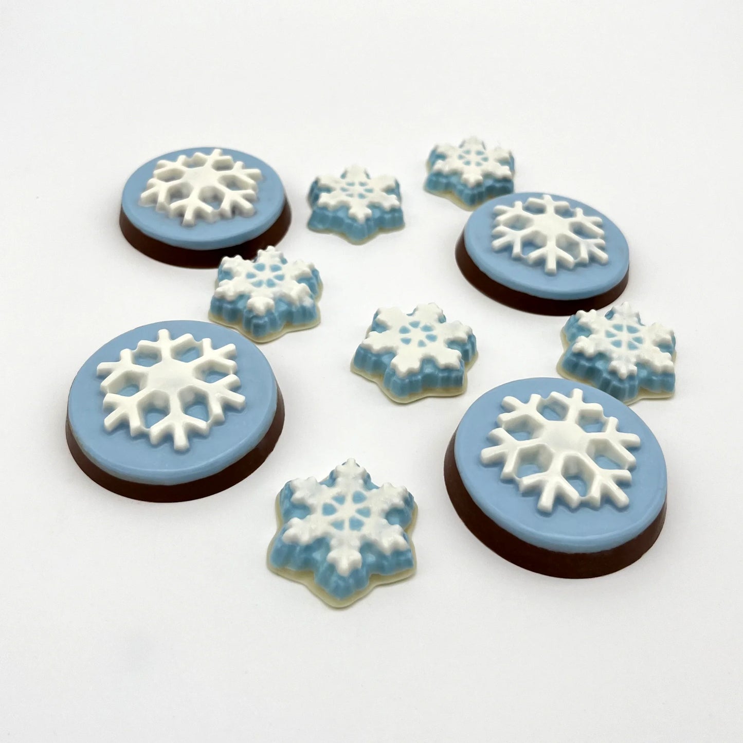 A collection of white and icy blue chocolate snowflake medallions and petite snowflakes.