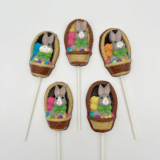 Grey and white chocolate bunnies adorned with green ribbons, in traditional brown woven baskets filled with colourful Easter eggs.
