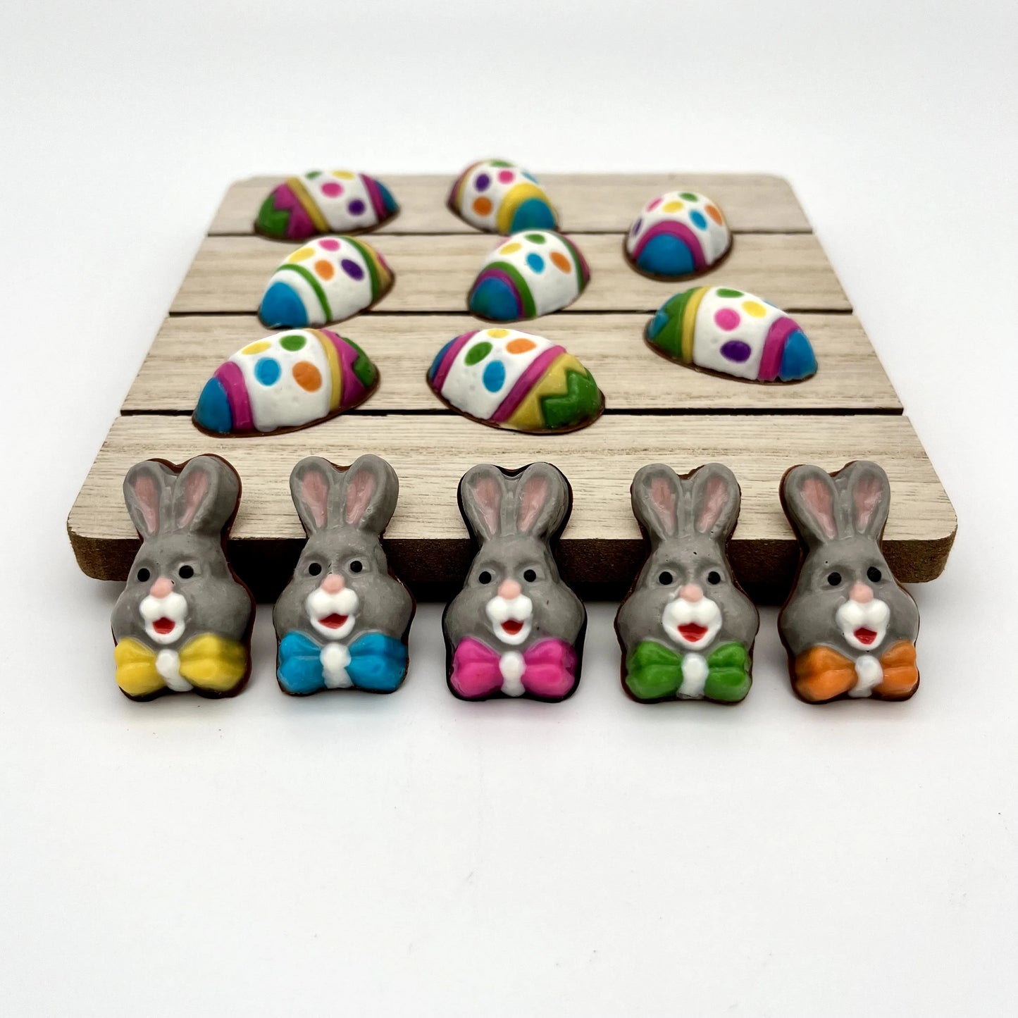 Mini chocolate bunnies, decorated in grey, white and pink with multi-colour bowties. Shown with our colourful, decorative chocolate Easter eggs.