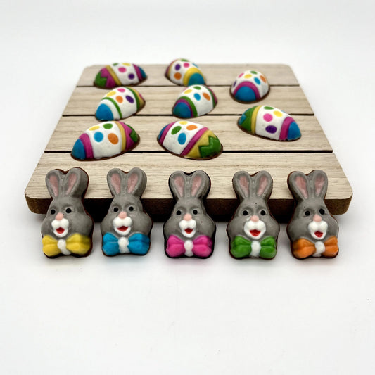 Mini chocolate bunnies, decorated in grey, white and pink with multi-colour bowties. Shown with our colourful, decorative chocolate Easter eggs.