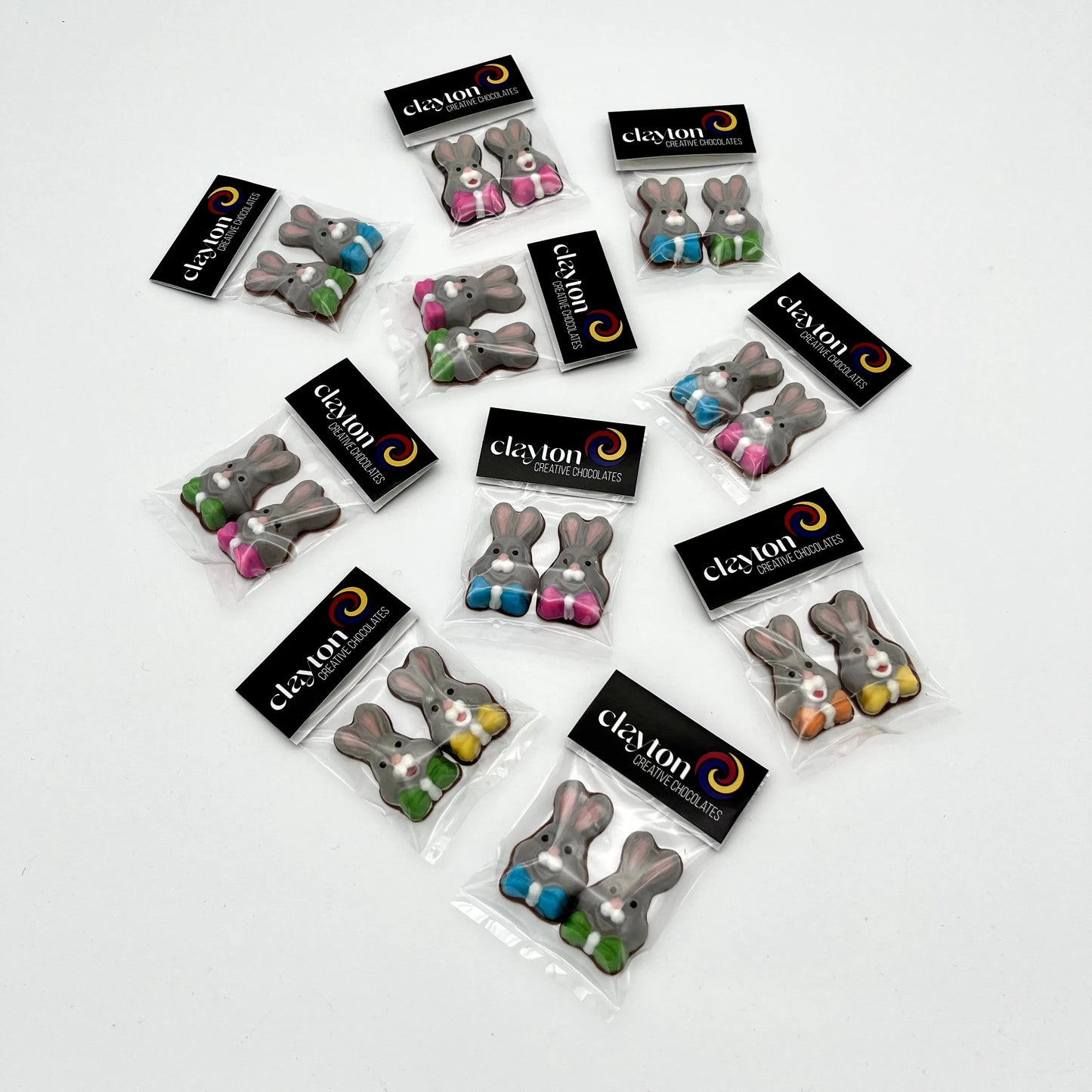 Mini chocolate bunnies, decorated in grey, white and pink with multi-colour bowties. Presented as 2-packs in Clayton Creative Chocolates packaging.