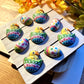 Hand-painted chocolates of yellow chicks in colourful eggs and Easter eggs, all decorated with dots and zigzags.