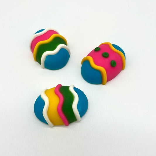 3 life-sized chocolate Easter eggs, decorated with stripes and dots in white and vibrant yellow, blue, pink and green.